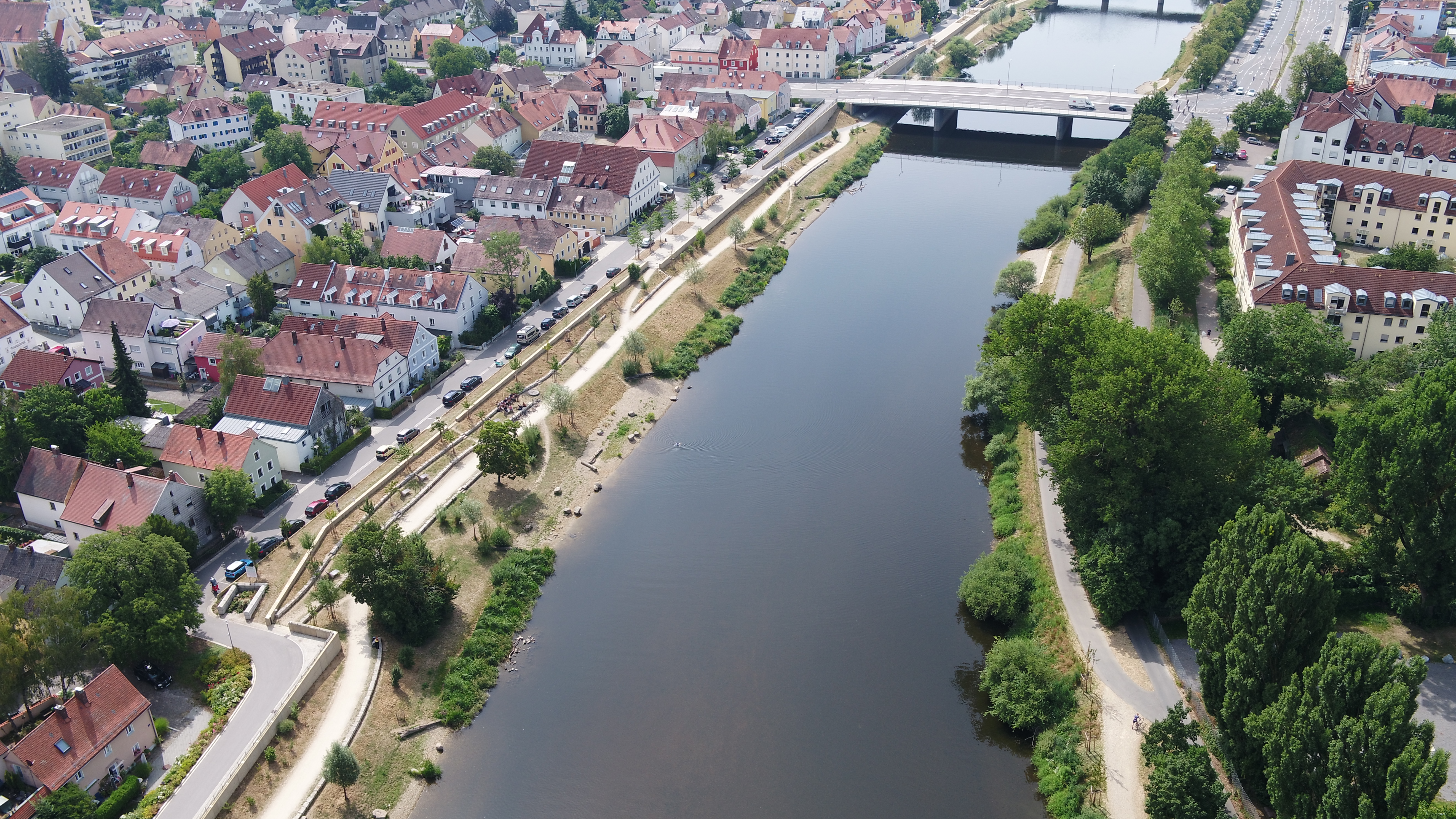 Luftbild des Flusses Regen, im oberen Bildrand eine Brücke über den Regen, auf beiden Uferseiten die neuen Hochwasserschutzmaßnahmen mit Bepflanzung und Bebauung 
