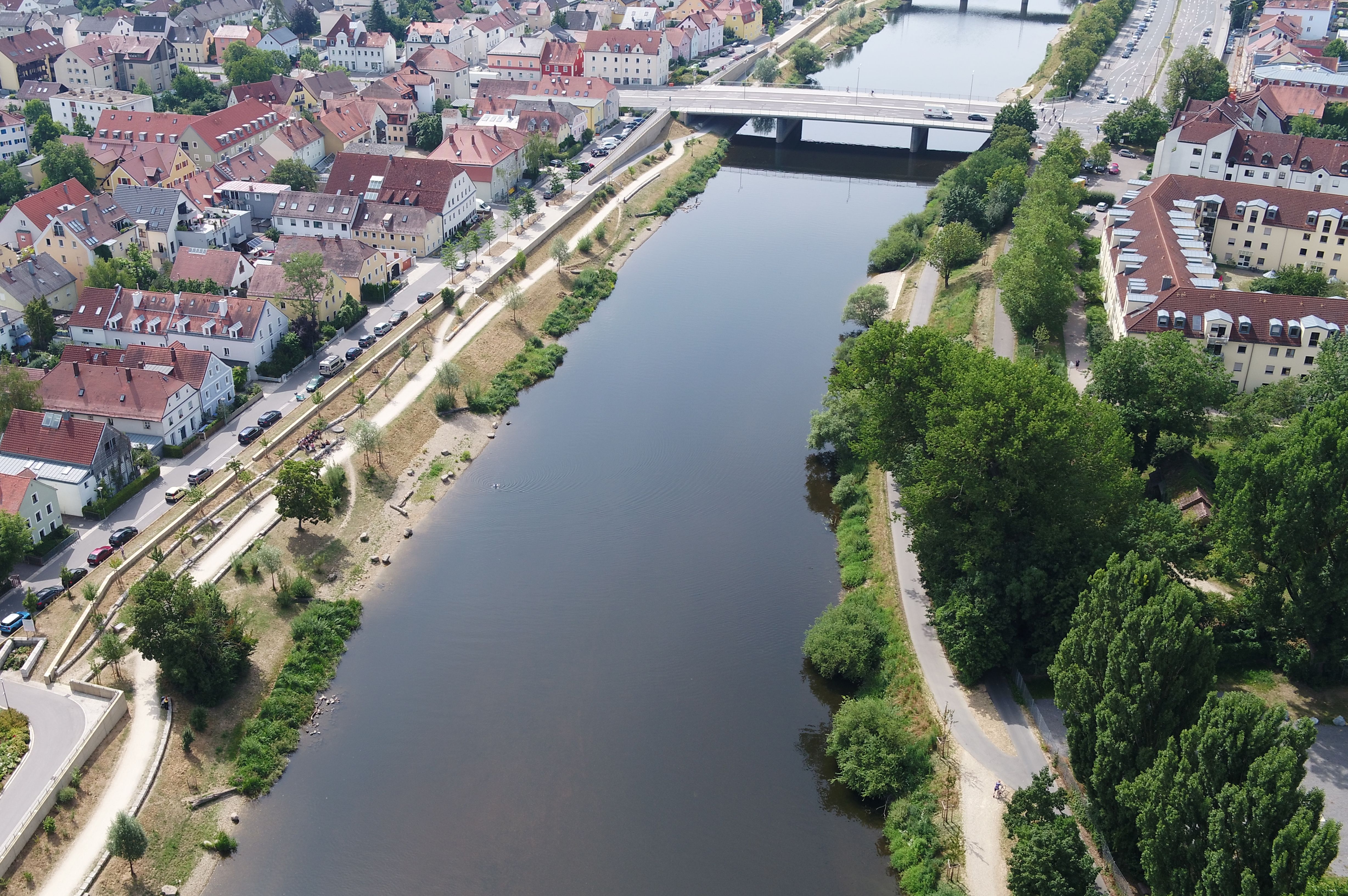 Luftbild des Flusses Regen, im oberen Bildrand eine Brücke über den Regen, auf beiden Uferseiten die neuen Hochwasserschutzmaßnahmen mit Bepflanzung und Bebauung 