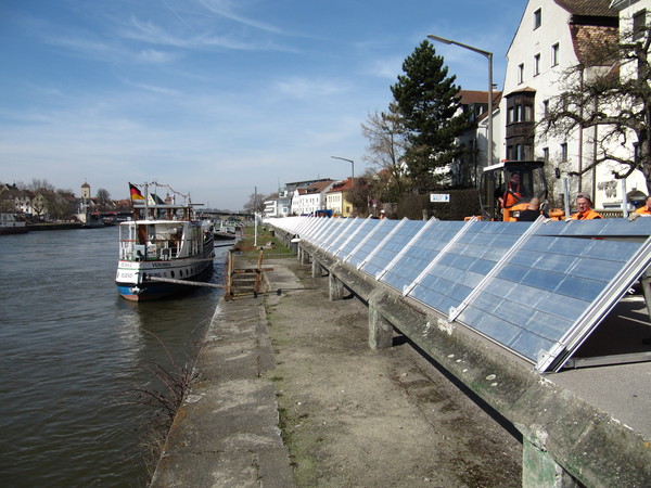 Mitarbeiter der Stadt beim Aufbauen der mobilen Hochwasserschutzwände an der Donau und auf der linken Seite liegt ein Schiff an der Schiffsanlegestelle