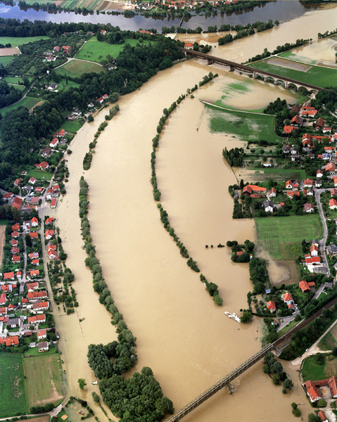 Luftbild auf die breite braune Donau, die an beiden Seiten über die Ufer getreten ist.